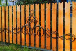 Wooden fence with elements of artistic forging